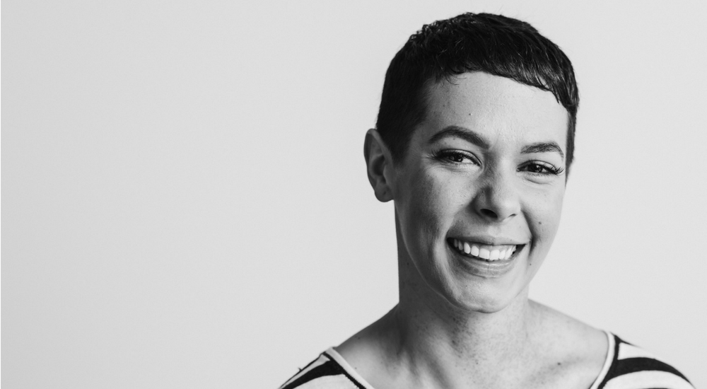 A woman with cropped hair looking at the camera and smiling.