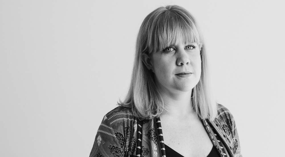 Blonde woman with a fringe looking straight at the camera with a slight smile