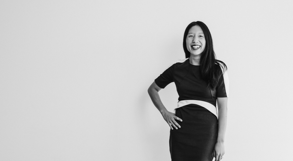 Asian woman standing with one hand on her hip and smiling